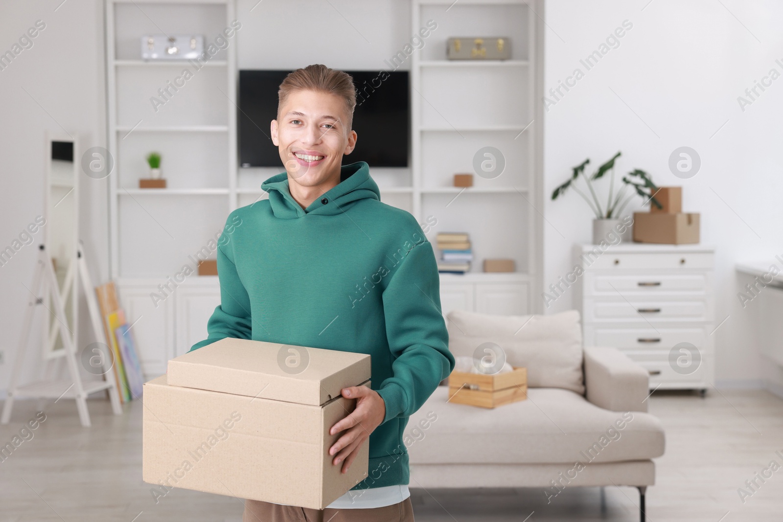 Photo of Happy man with moving boxes in new apartment. Housewarming party