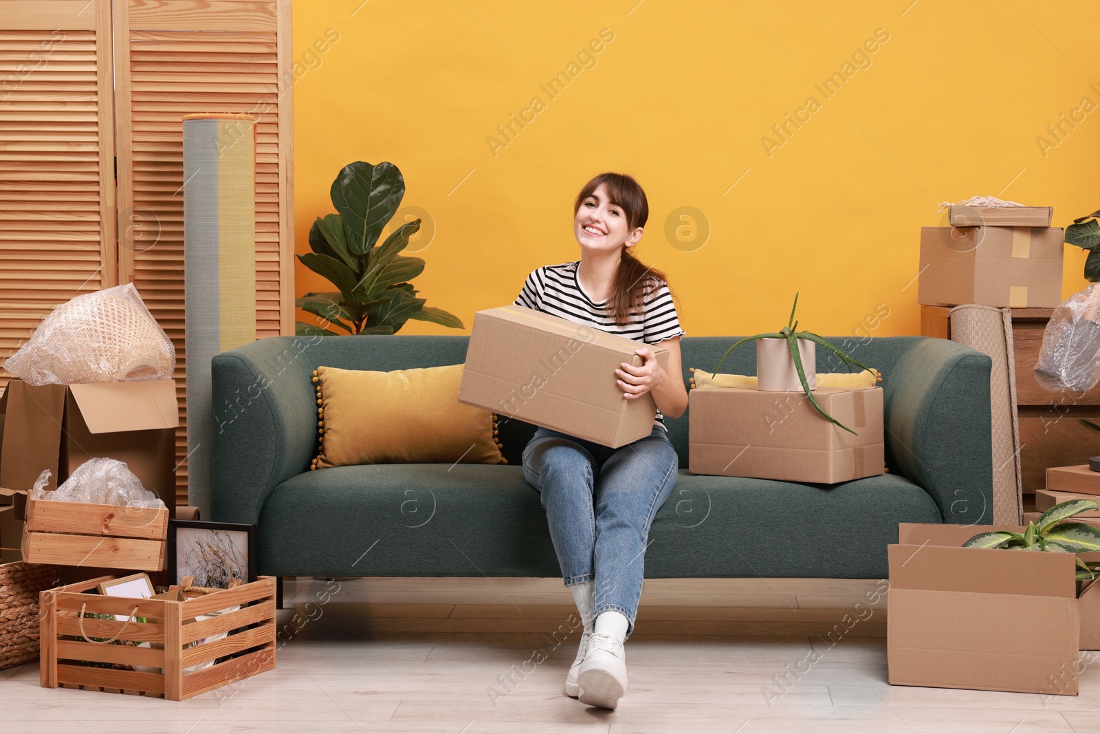 Photo of Happy woman with moving boxes in new apartment. Housewarming party