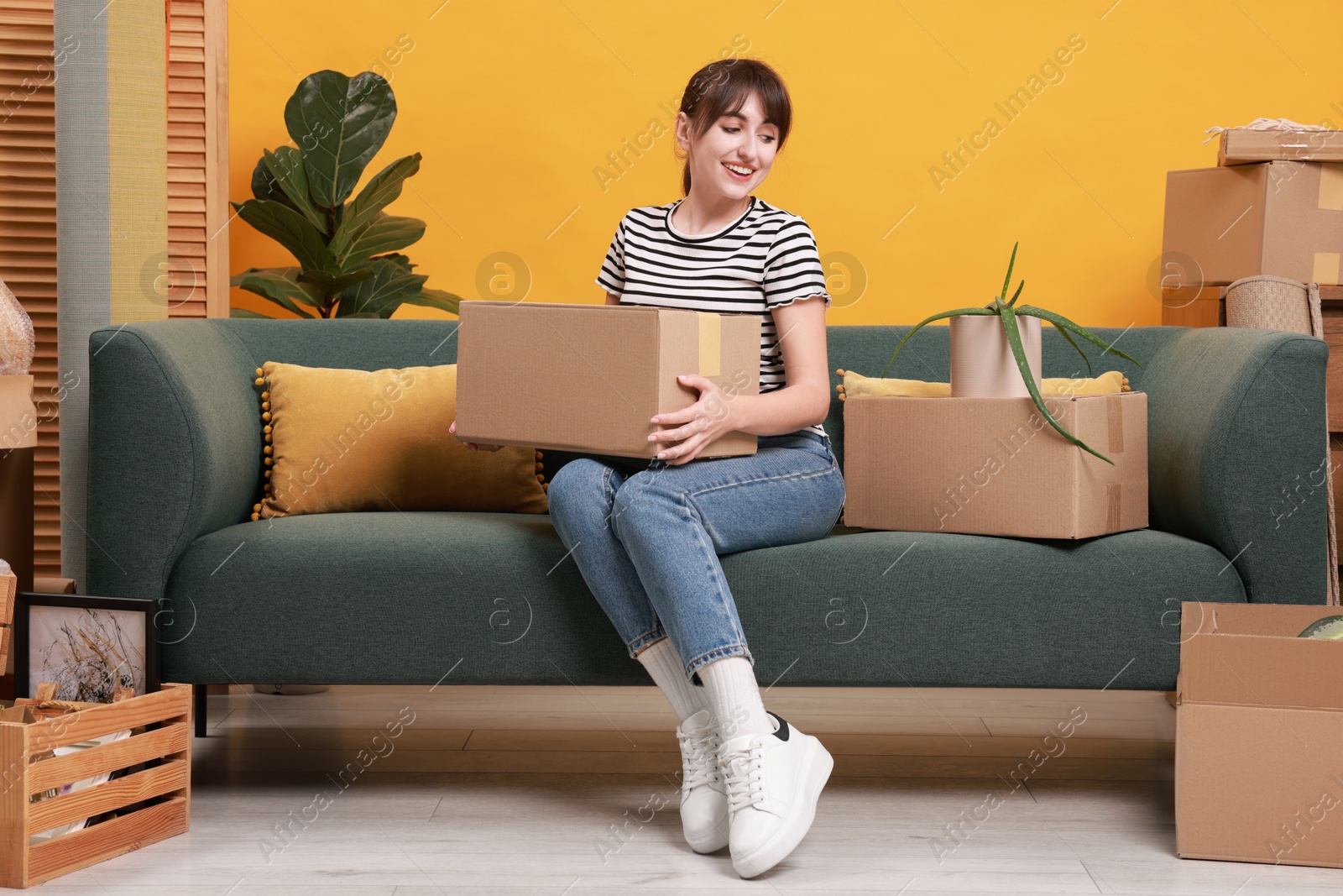 Photo of Happy woman with moving boxes in new apartment. Housewarming party