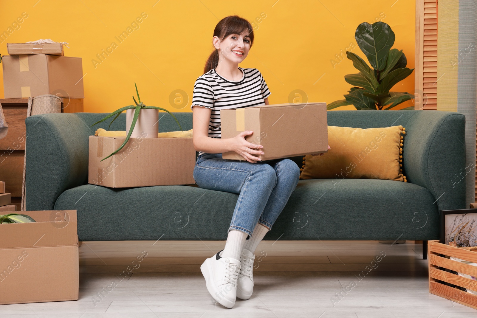 Photo of Happy woman with moving boxes in new apartment. Housewarming party