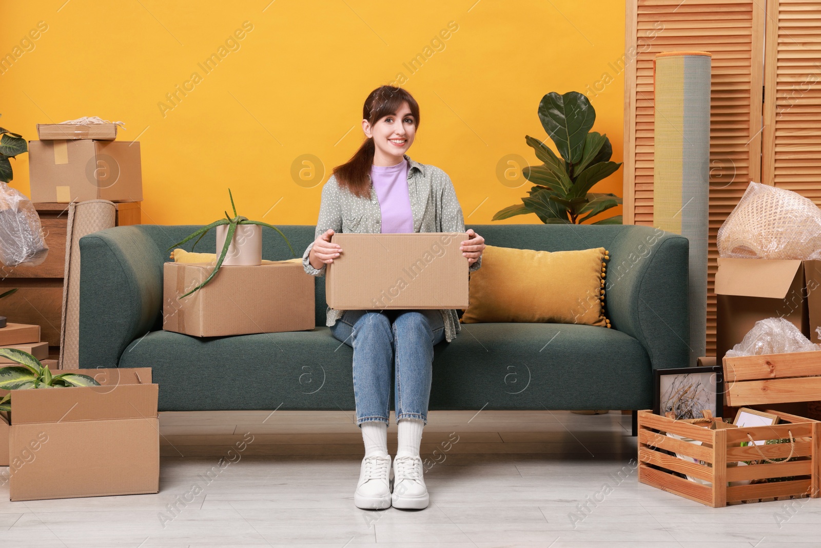 Photo of Happy woman with moving boxes in new apartment. Housewarming party