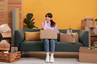 Photo of Happy woman with moving boxes in new apartment. Housewarming party