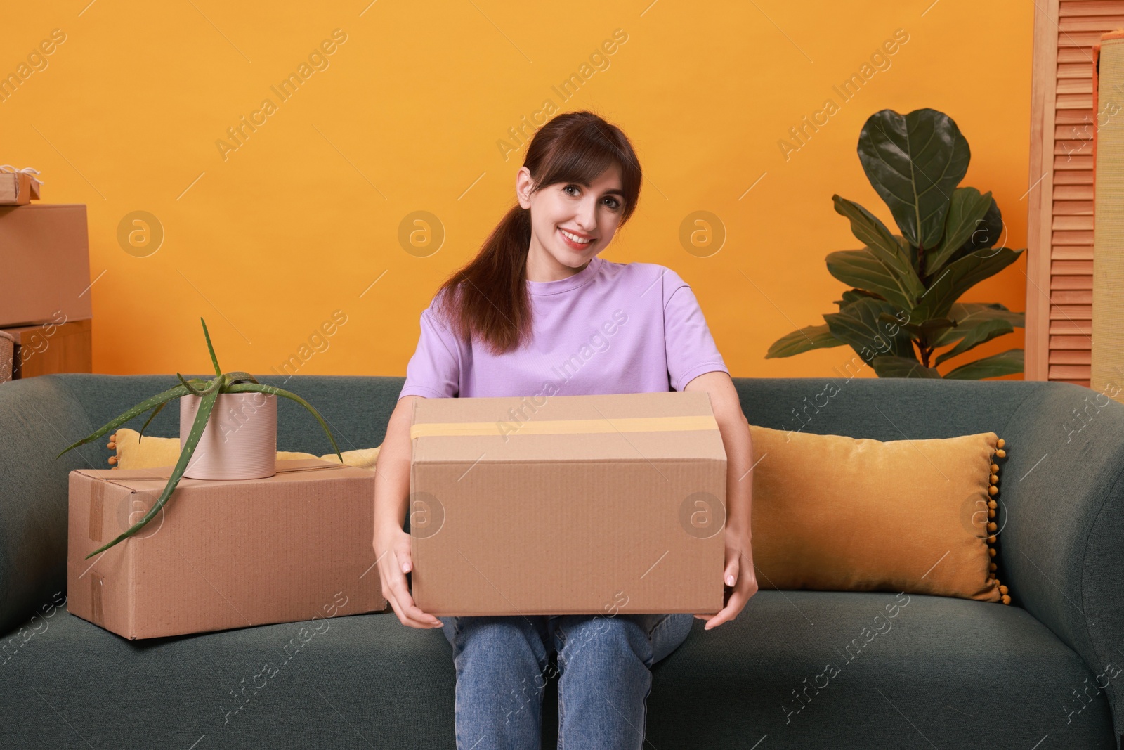 Photo of Happy woman with moving boxes in new apartment. Housewarming party