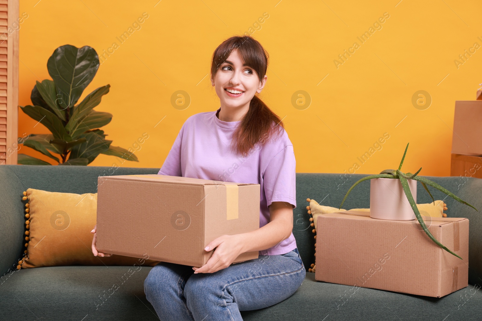 Photo of Happy woman with moving boxes in new apartment. Housewarming party