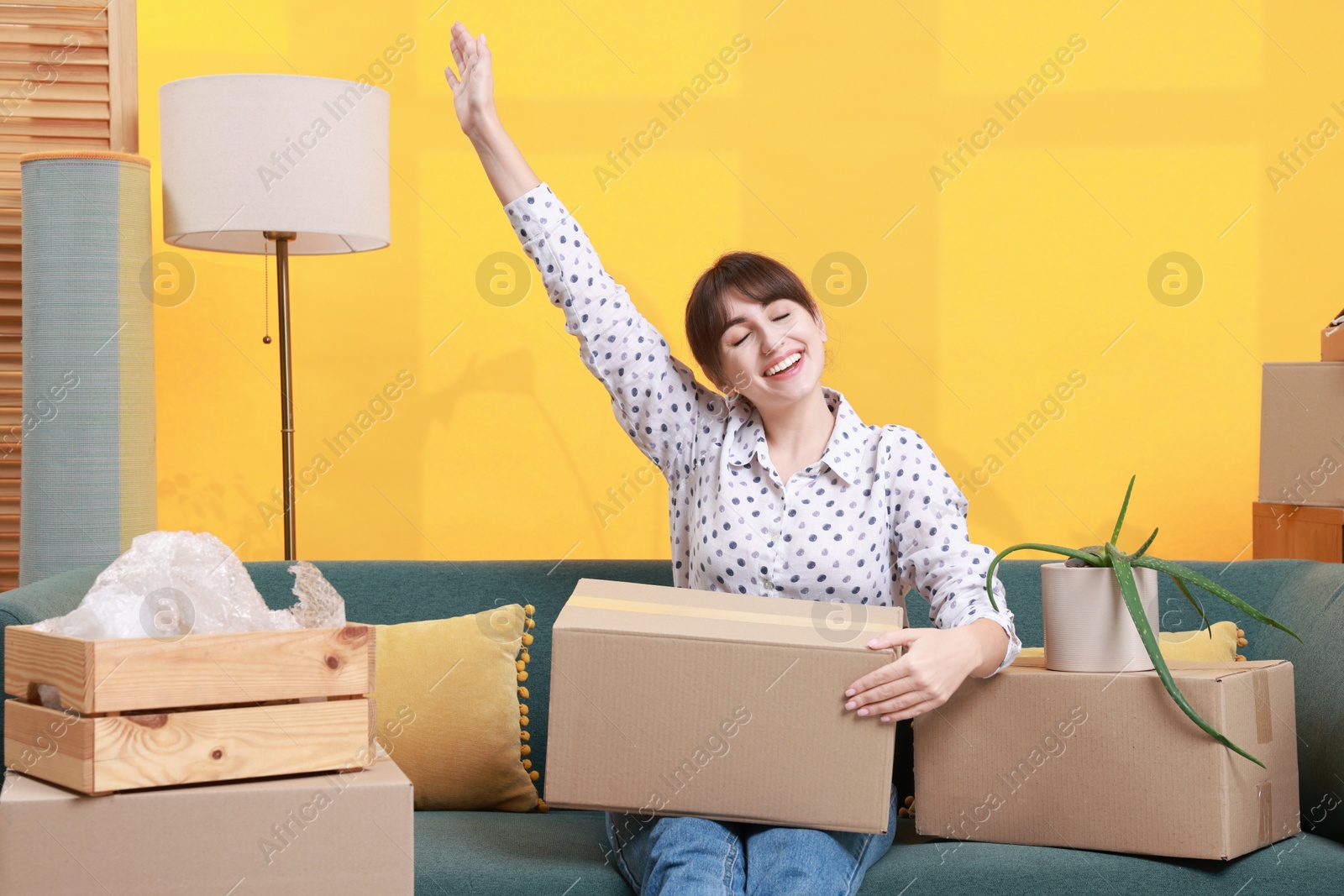 Photo of Happy woman with moving boxes in new apartment. Housewarming party