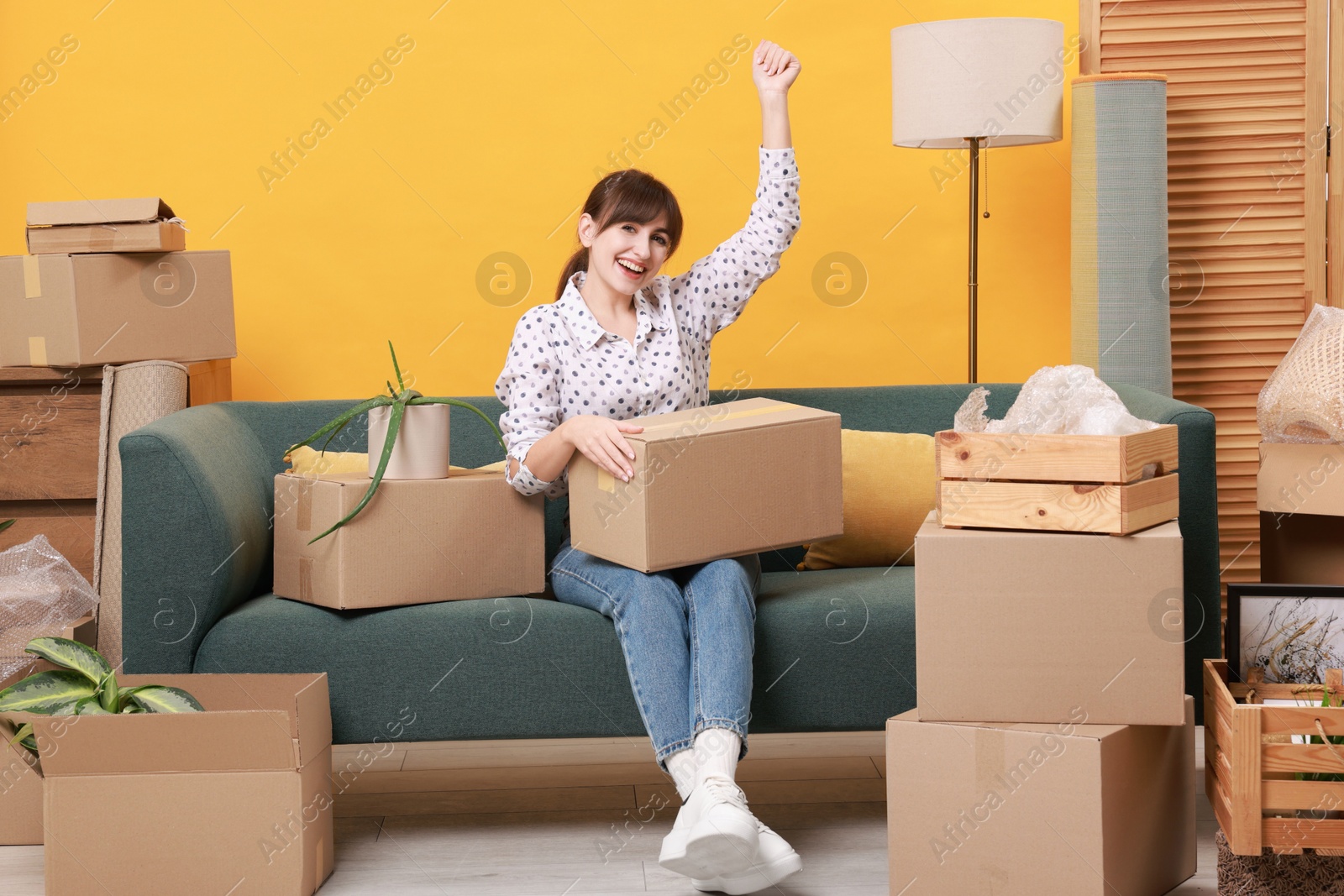 Photo of Happy woman with moving boxes in new apartment. Housewarming party