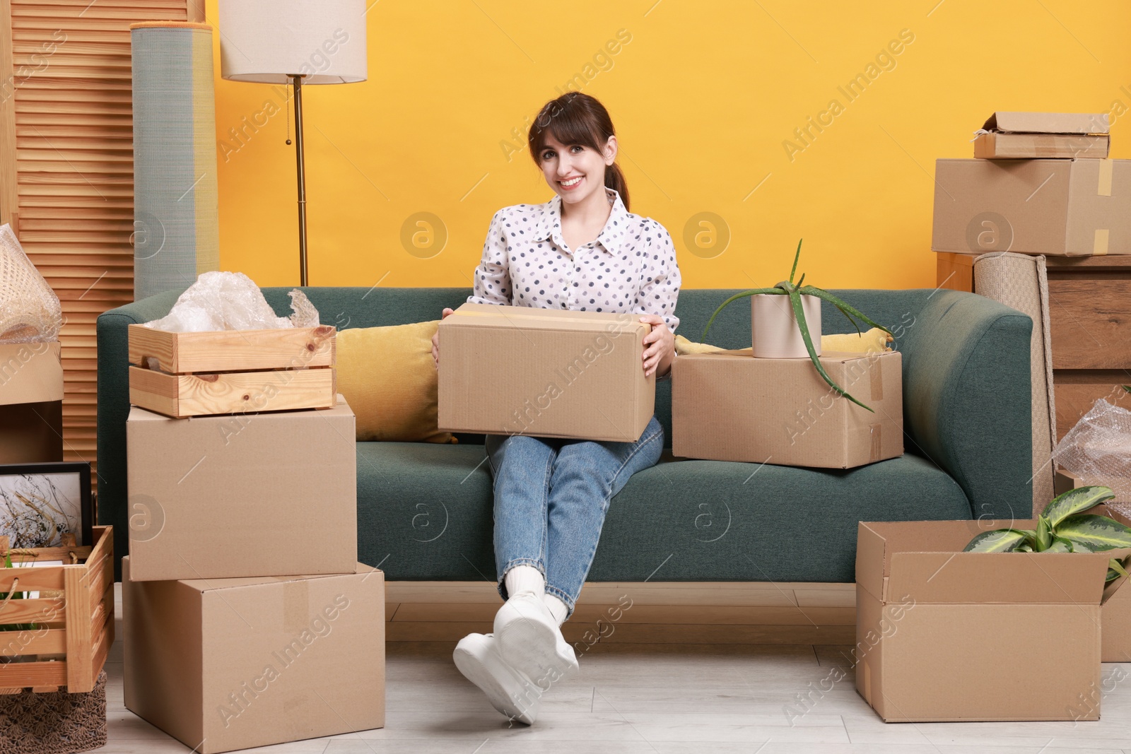 Photo of Happy woman with moving boxes in new apartment. Housewarming party