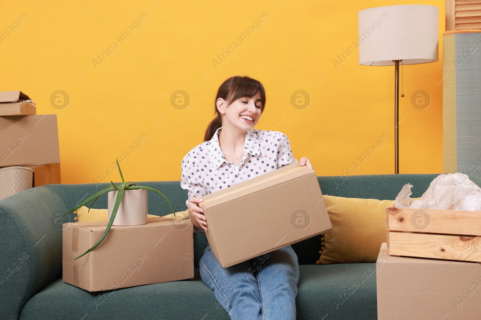 Photo of Happy woman with moving boxes in new apartment. Housewarming party