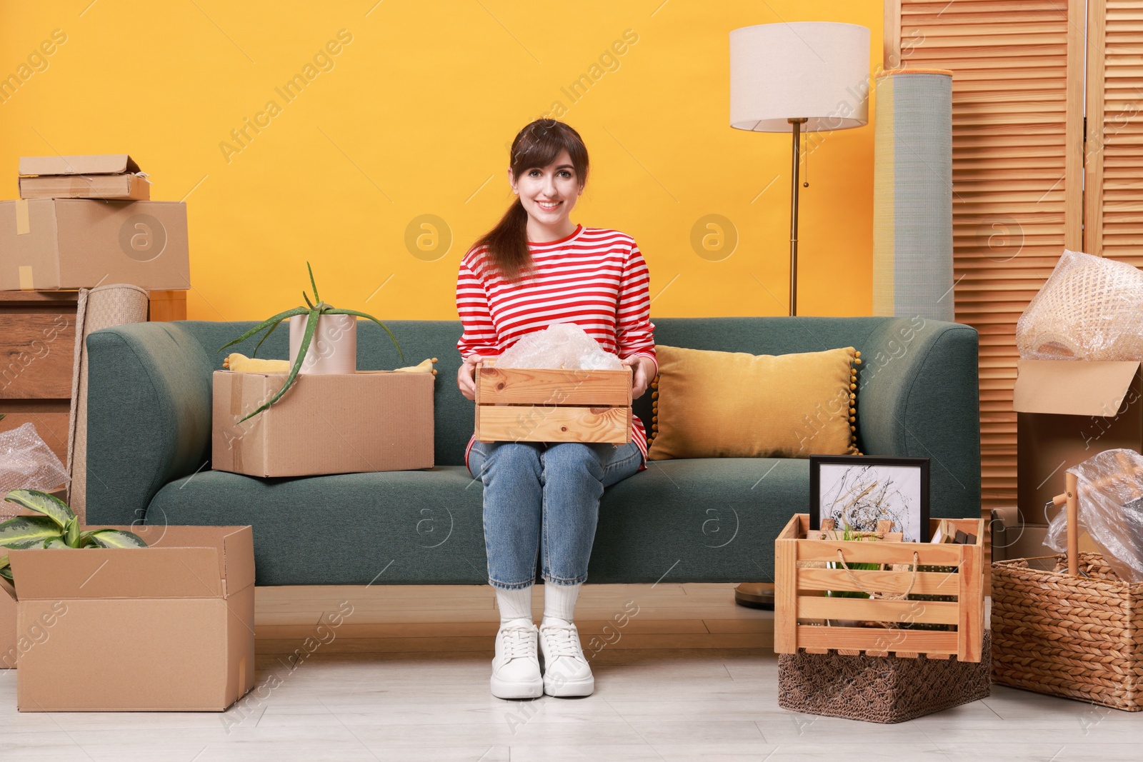 Photo of Happy woman with moving boxes in new apartment. Housewarming party