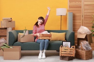 Happy woman with moving boxes in new apartment. Housewarming party