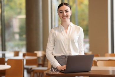 Photo of Beautiful woman in stylish outfit working on laptop indoors