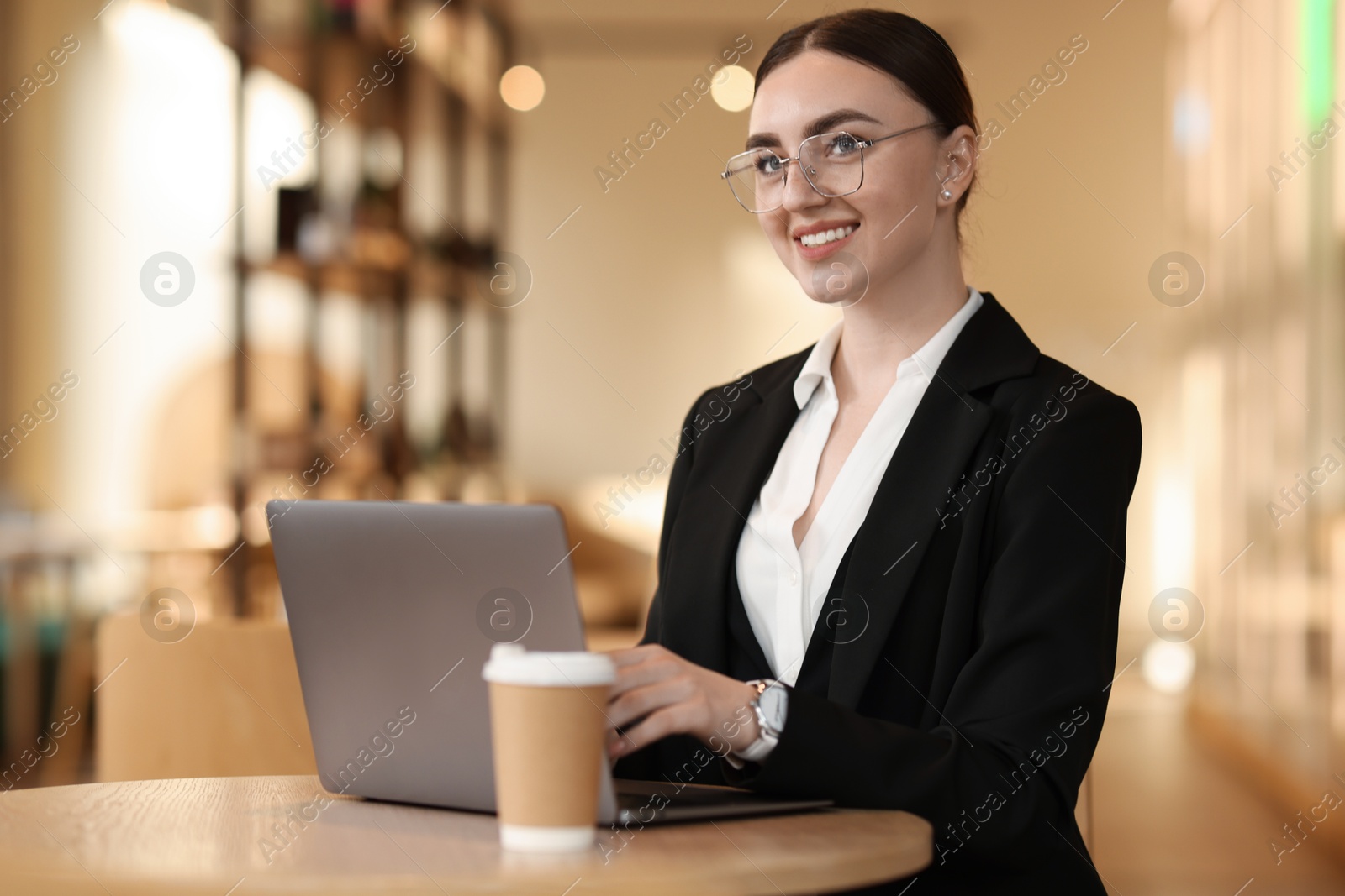 Photo of Woman in stylish formal suit working on laptop at table indoors