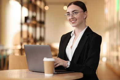 Photo of Woman in stylish formal suit working on laptop at table indoors