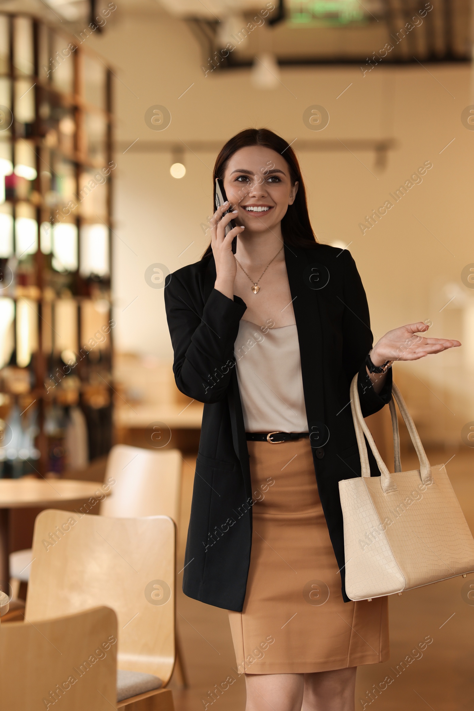 Photo of Woman in stylish formal suit talking on phone indoors