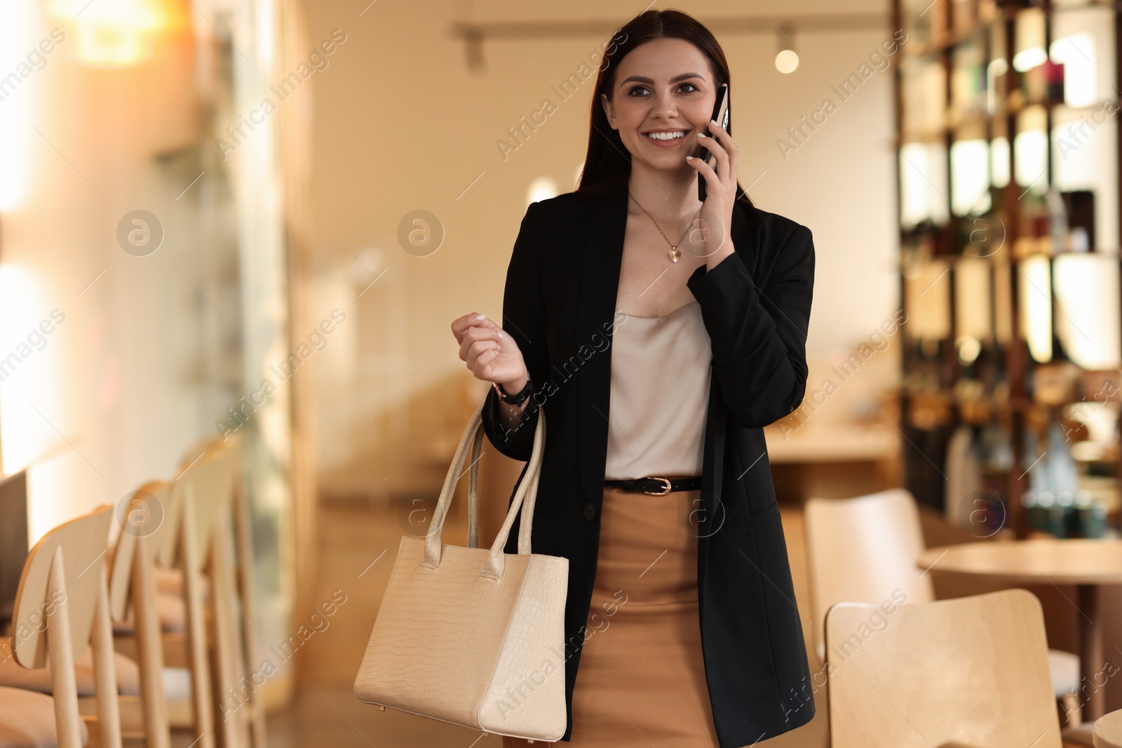 Photo of Woman in stylish formal suit talking on phone indoors. Space for text