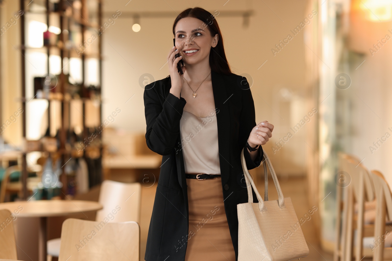 Photo of Woman in stylish formal suit talking on phone indoors