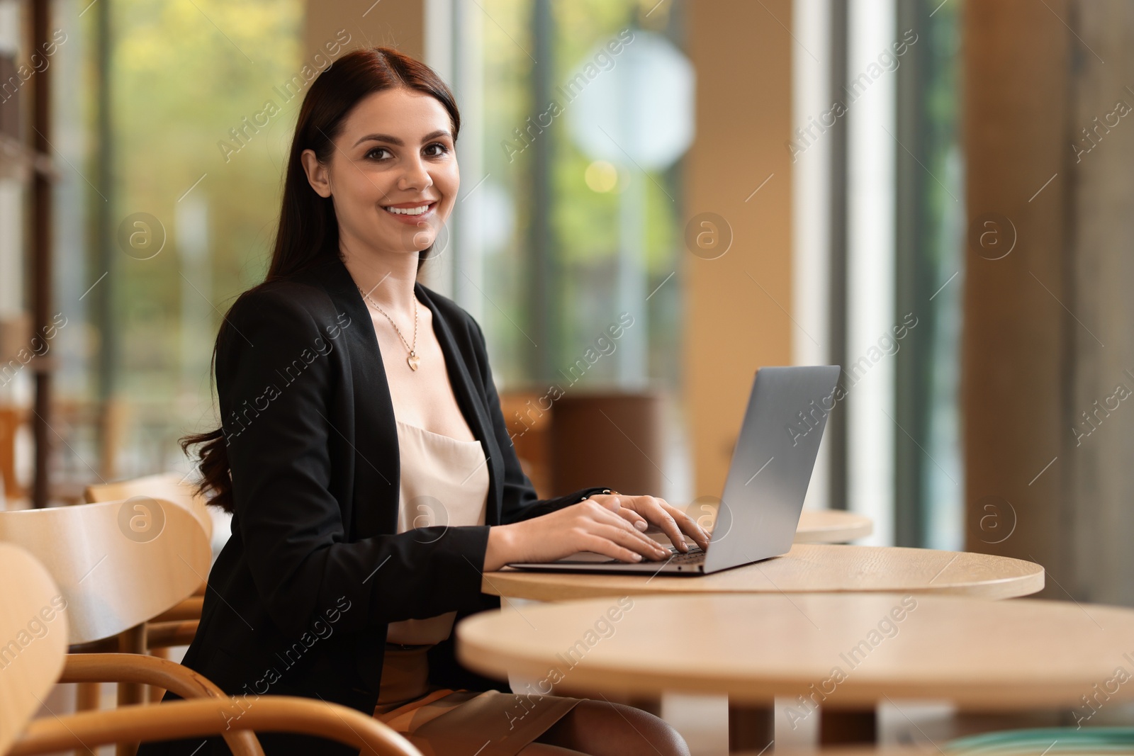 Photo of Woman in stylish formal suit working on laptop at table indoors