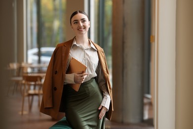 Photo of Woman in stylish formal suit with tablet indoors. Space for text