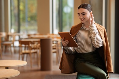 Photo of Woman in stylish formal suit with tablet indoors. Space for text