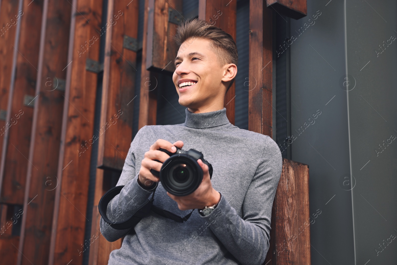 Photo of Professional photographer with modern camera near wall outdoors