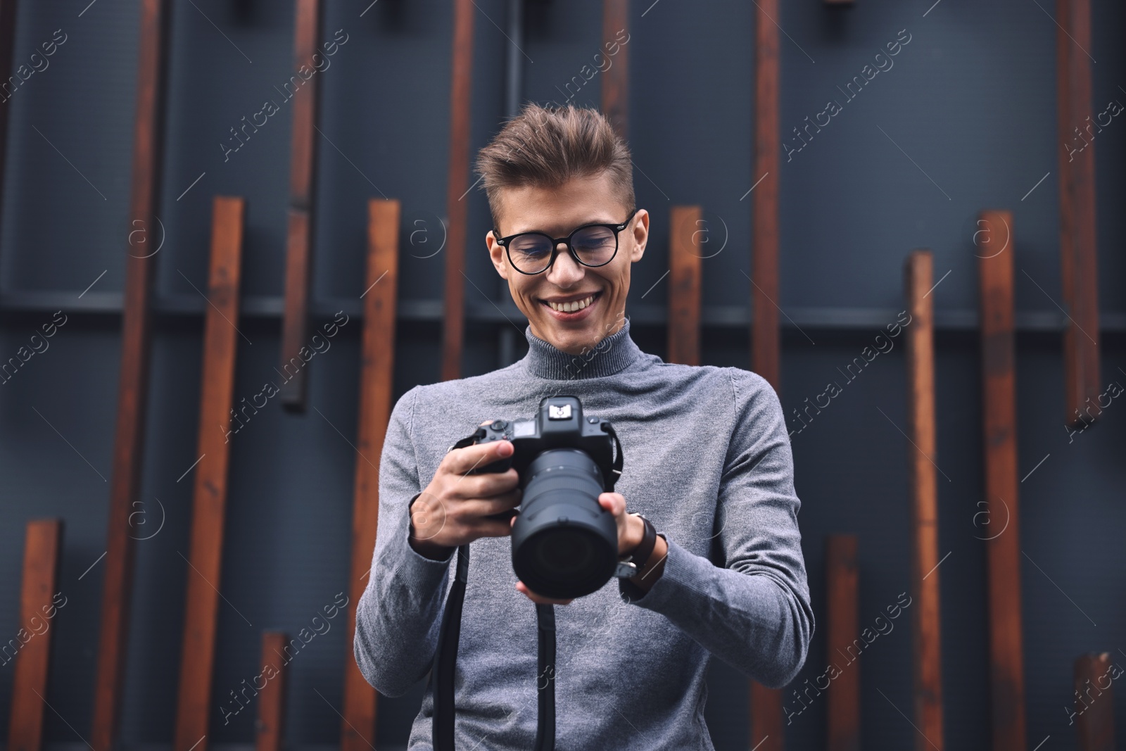 Photo of Professional photographer with modern camera near wall outdoors