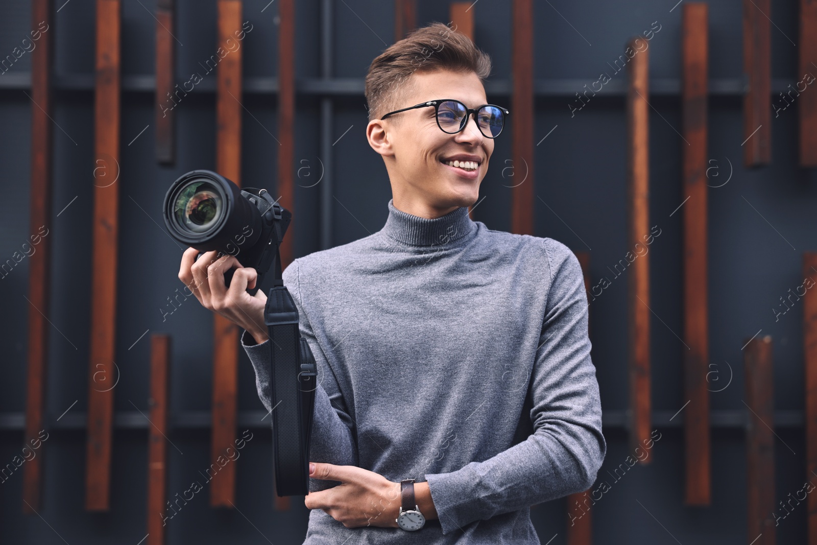 Photo of Professional photographer with modern camera near wall outdoors