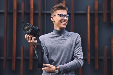 Photo of Professional photographer with modern camera near wall outdoors