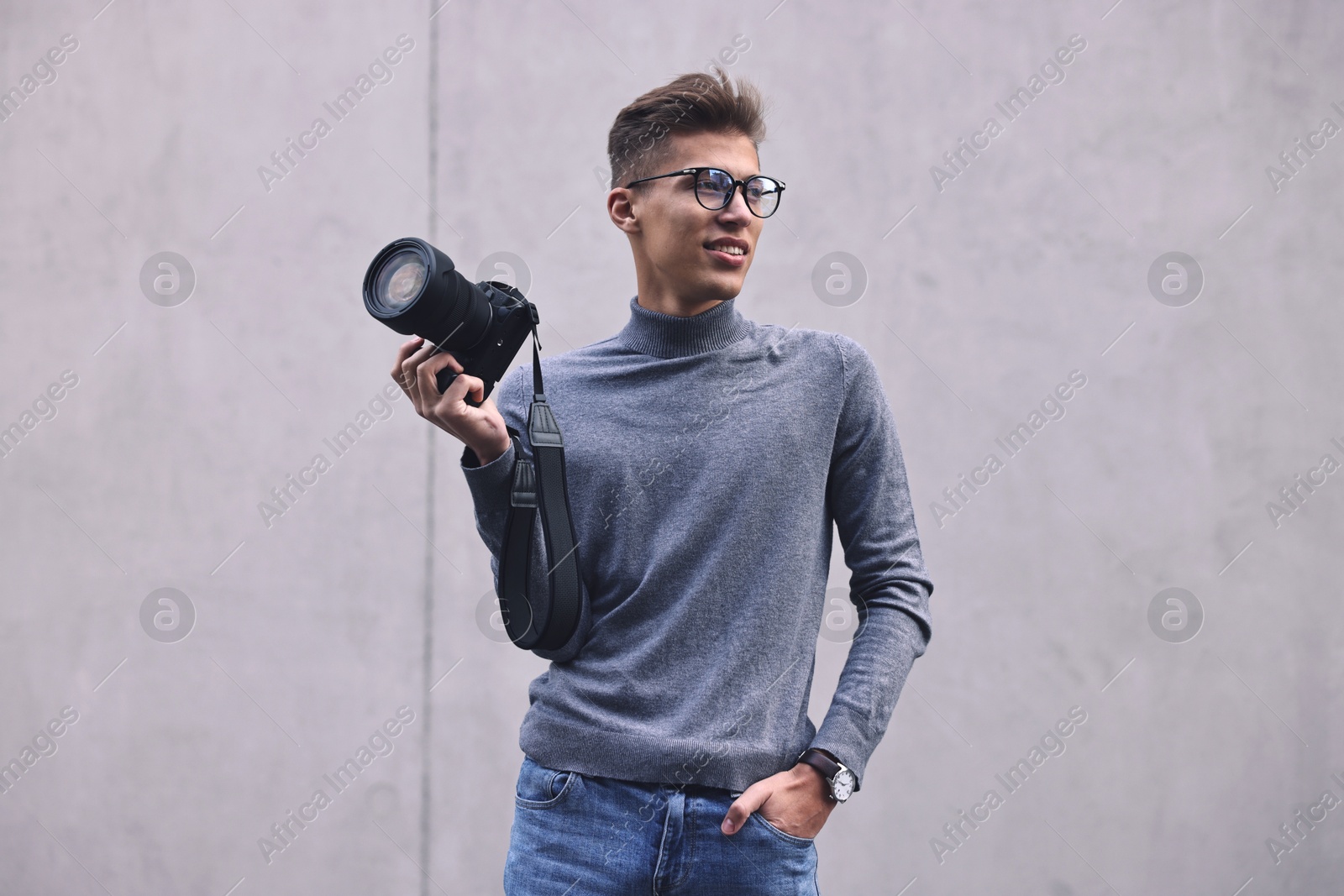 Photo of Professional photographer with camera near grey wall outdoors