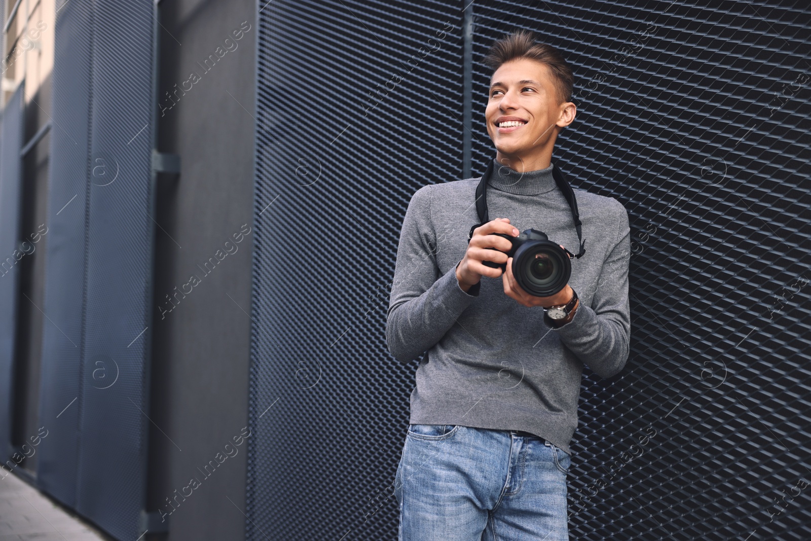 Photo of Professional photographer with modern camera near wall outdoors. Space for text