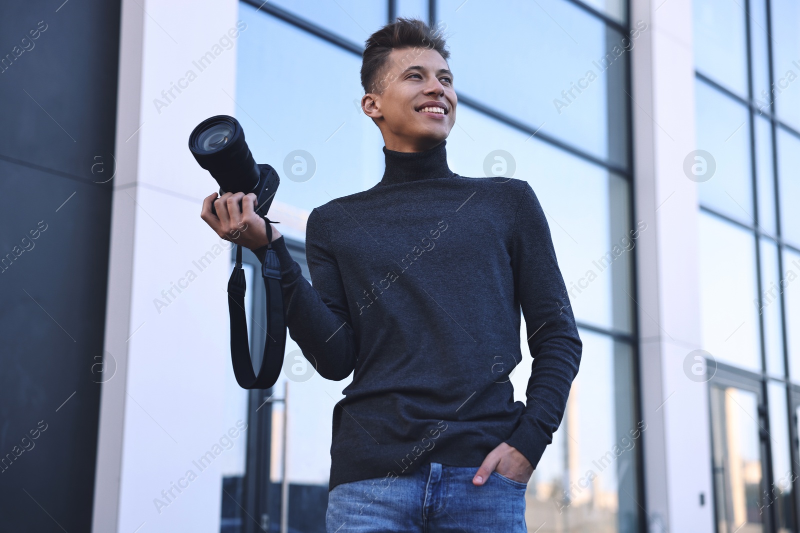 Photo of Professional photographer with camera near building outdoors, low angle view