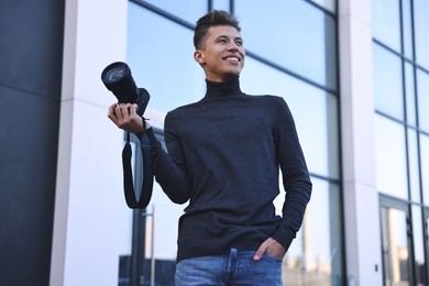 Professional photographer with camera near building outdoors, low angle view