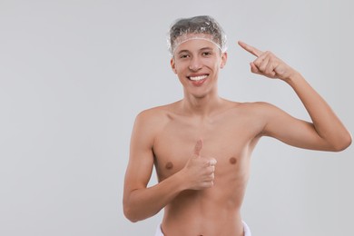 Man in shower cap on light grey background, space for text