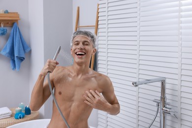 Man with cap taking shower in bathroom