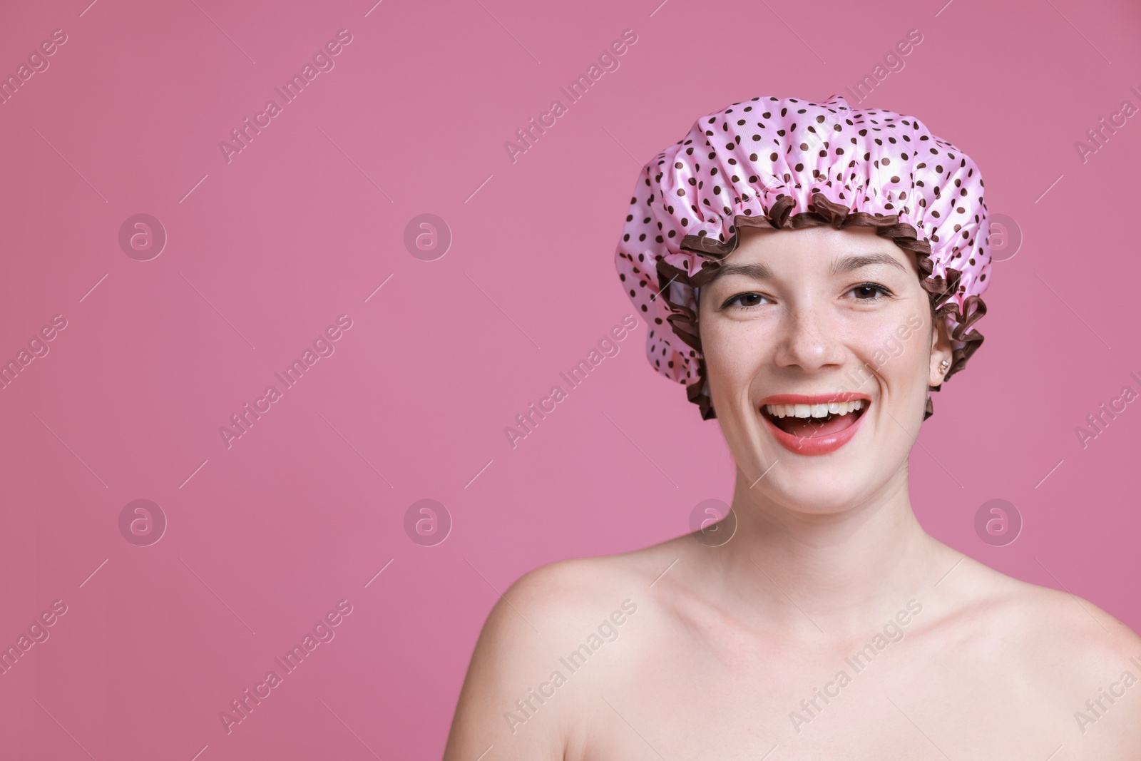 Photo of Woman in shower cap on pink background, space for text