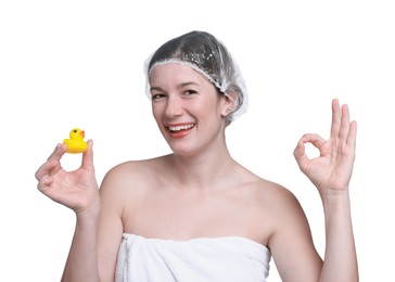 Photo of Woman with shower cap and bath duck showing ok gesture on white background