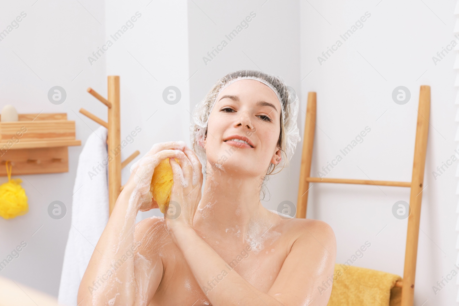 Photo of Woman with cap and mesh sponge taking shower in bathroom