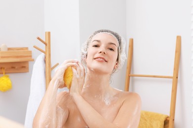 Photo of Woman with cap and mesh sponge taking shower in bathroom