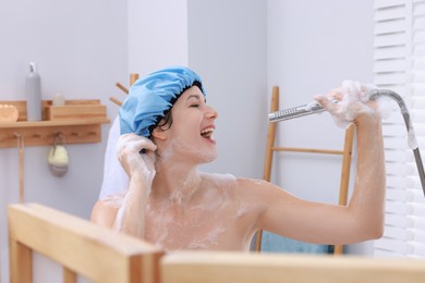 Photo of Woman with cap singing while taking shower in bathroom