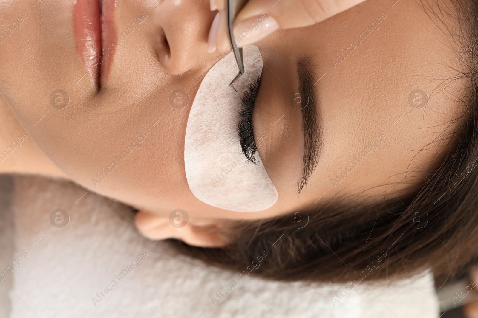 Photo of Woman undergoing lash extensions procedure in beauty salon, top view