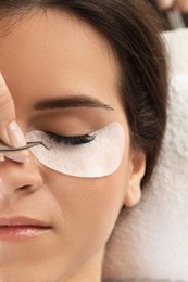 Photo of Woman undergoing lash extensions procedure in beauty salon, top view