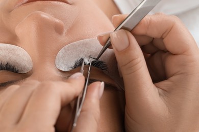 Photo of Young woman undergoing lash extensions procedure, closeup