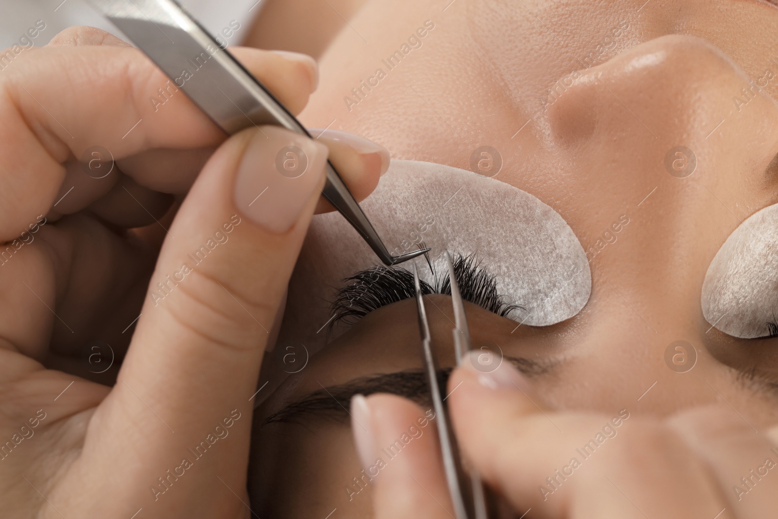 Photo of Young woman undergoing lash extensions procedure, closeup