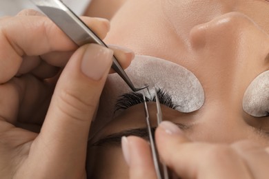 Photo of Young woman undergoing lash extensions procedure, closeup