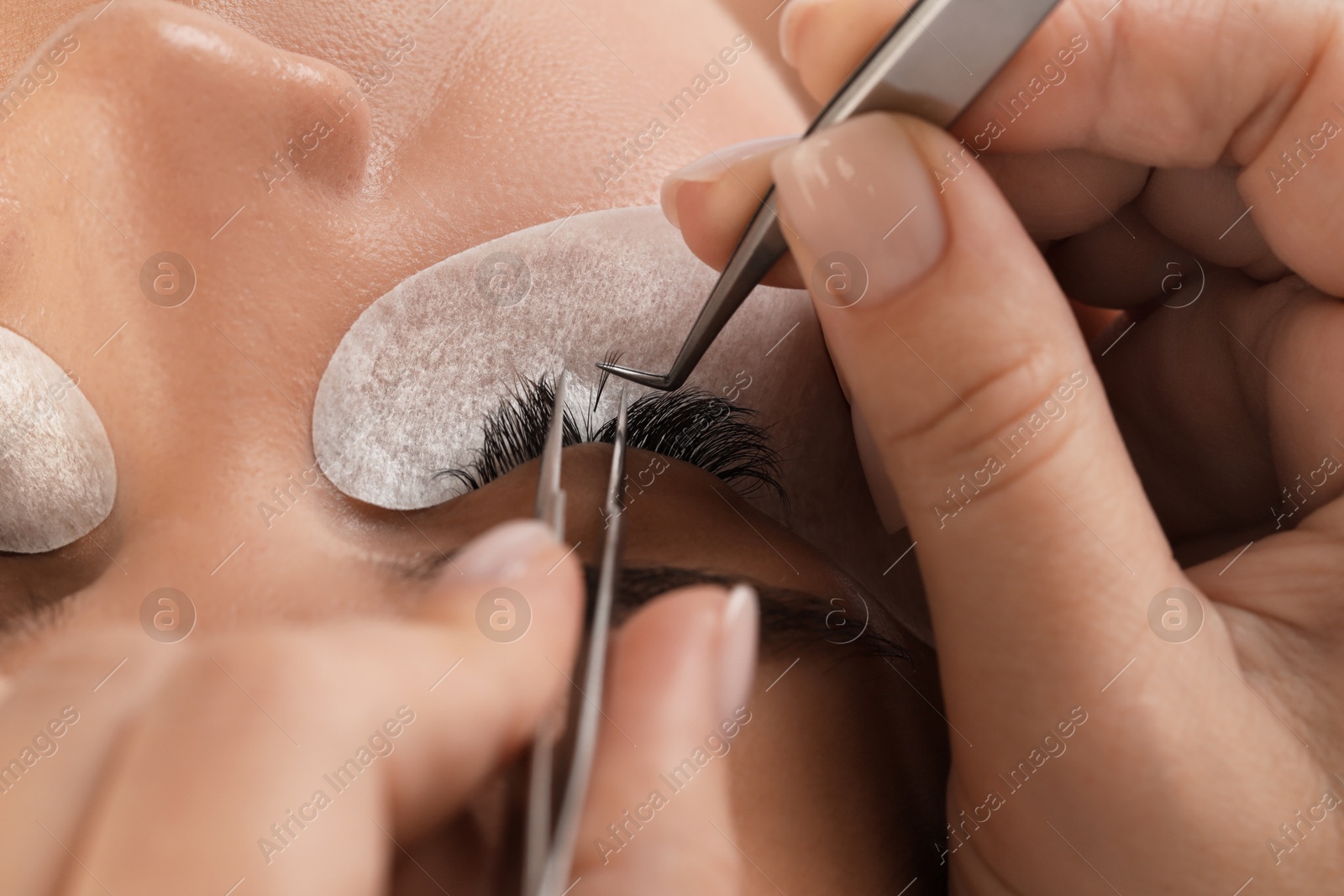 Photo of Young woman undergoing lash extensions procedure, closeup