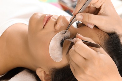 Woman undergoing lash extensions procedure in beauty salon, closeup