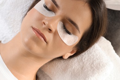 Photo of Young woman undergoing lash extensions procedure in beauty salon, closeup