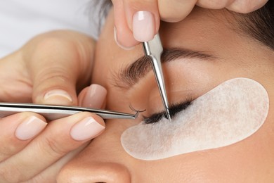 Photo of Woman undergoing lash extensions procedure in beauty salon, closeup