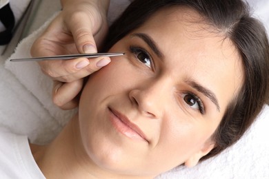 Photo of Woman undergoing lash extensions procedure in beauty salon, top view