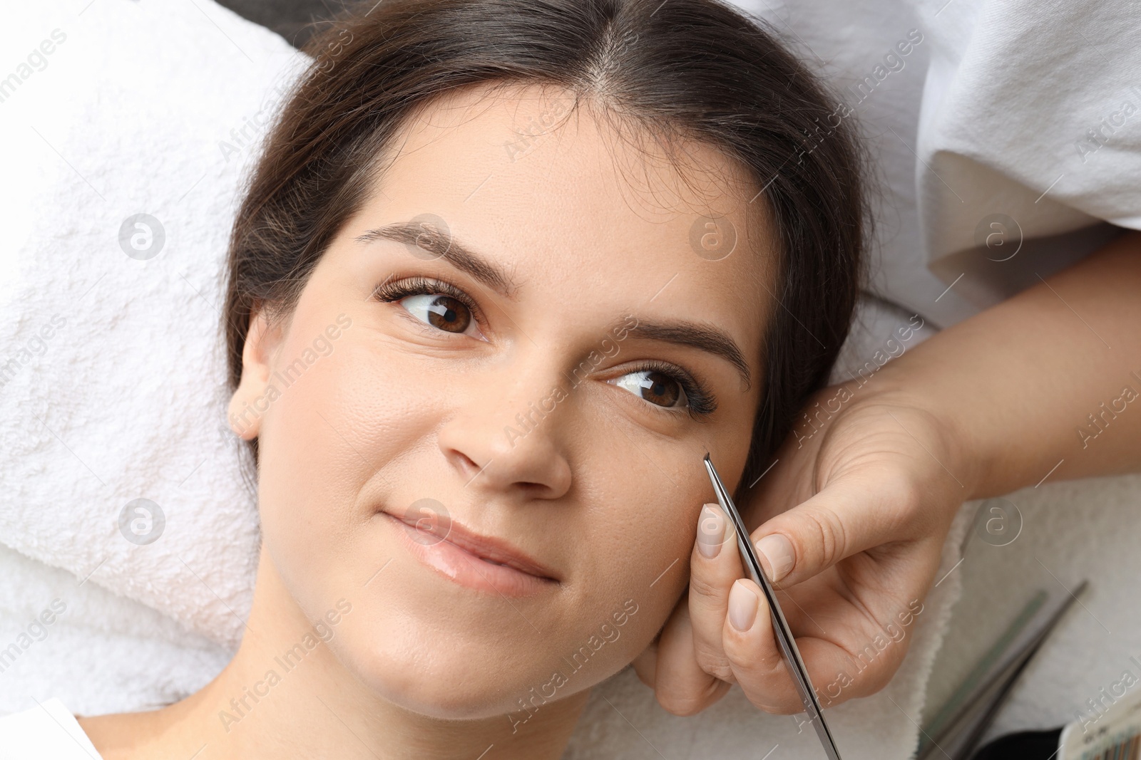 Photo of Woman undergoing lash extensions procedure in beauty salon, top view