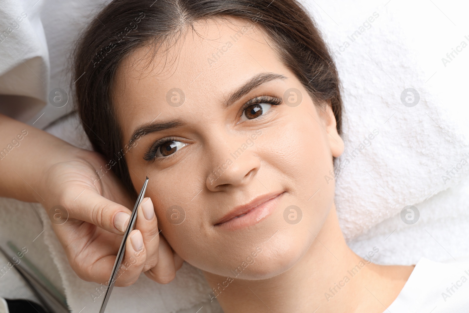 Photo of Woman undergoing lash extensions procedure in beauty salon, top view